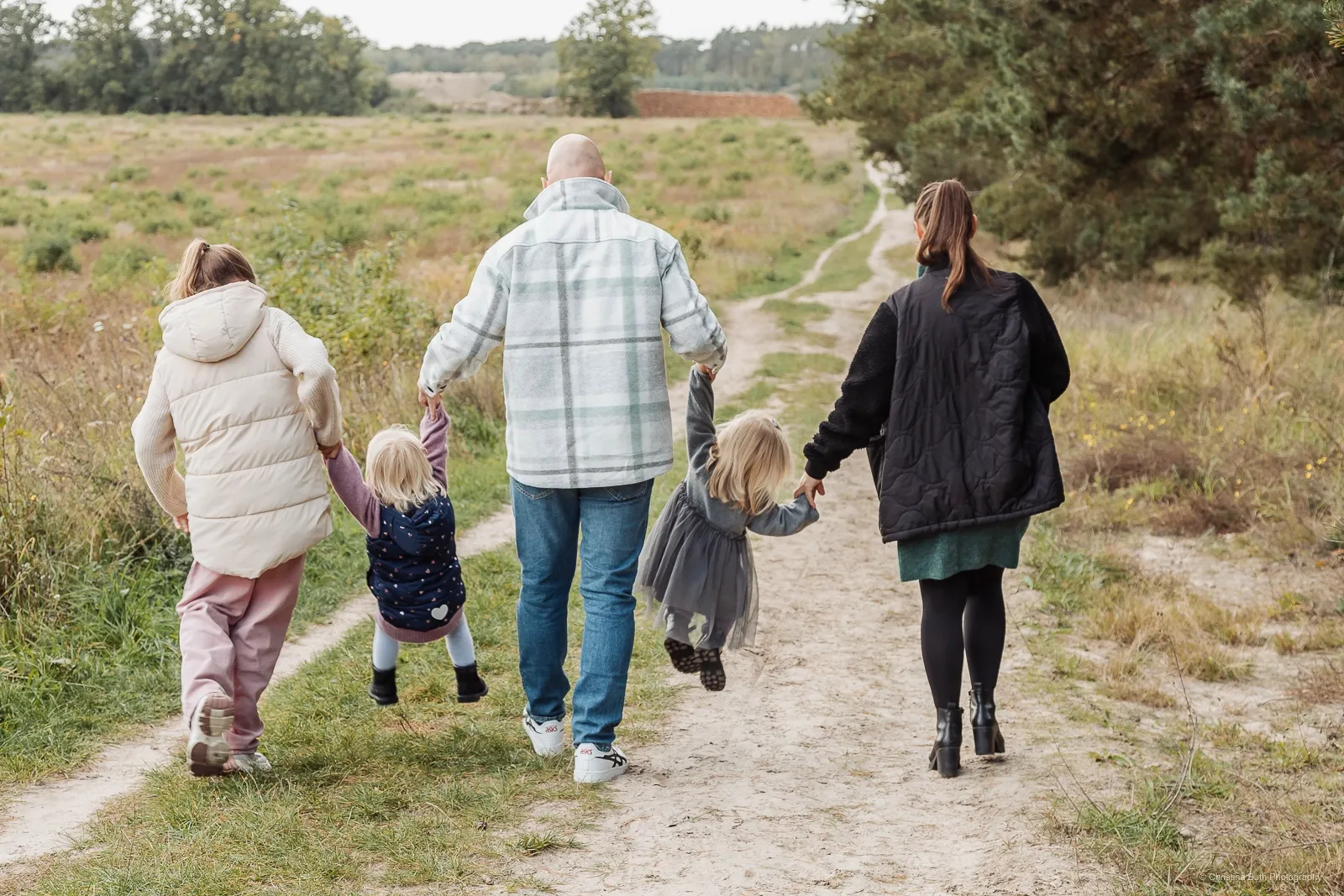 Familie spaziert Hand in Hand durch herbstliche Natur